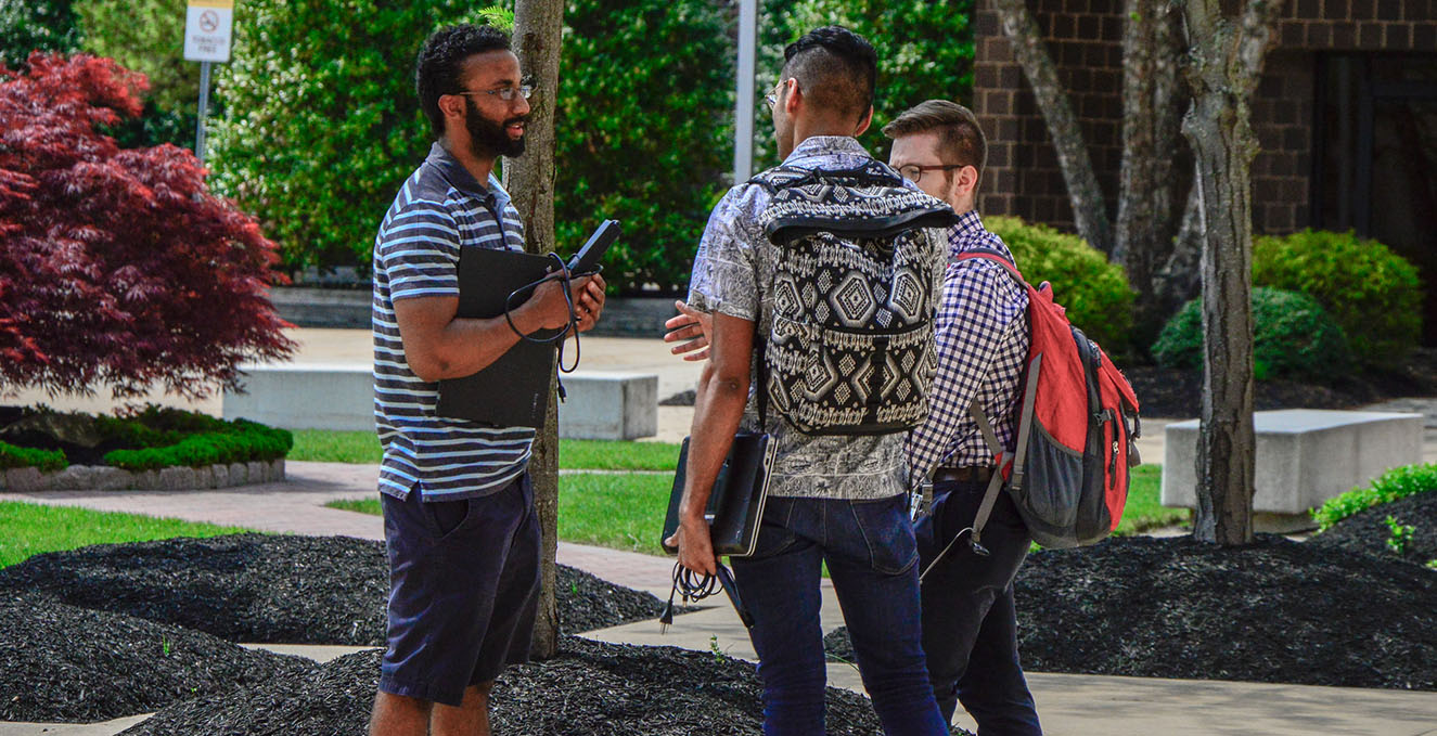 Three students standing outside talking on the Stratford campus