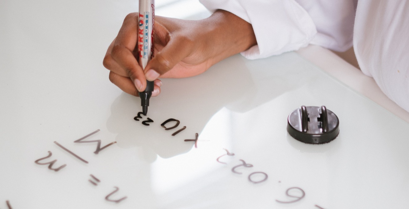 student writing a formula on a white board